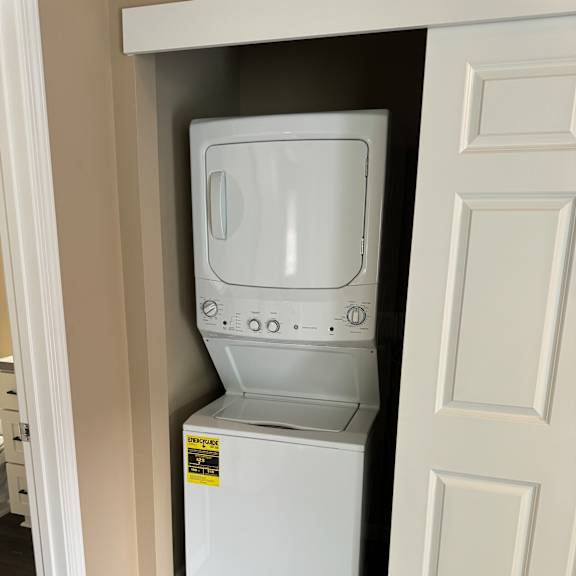 A white microwave oven is installed in a kitchen cabinet.
