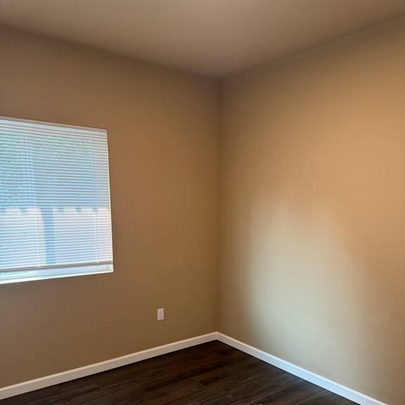 A room with a window and wooden flooring.