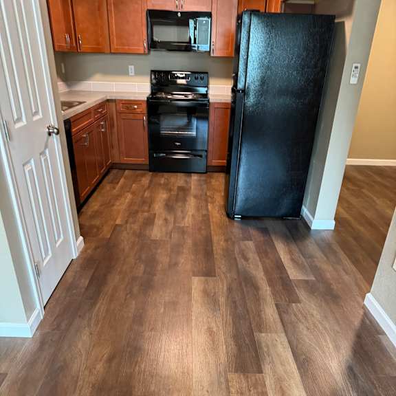 A kitchen with a black TV mounted above a white fridge.