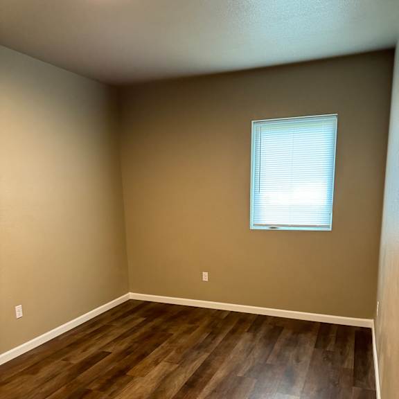 A room with a window and a wooden wall.