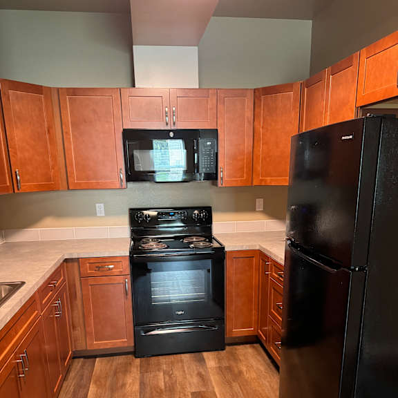 A kitchen with wooden cabinets and a black countertop.