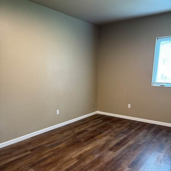 A room with a window and wooden flooring.