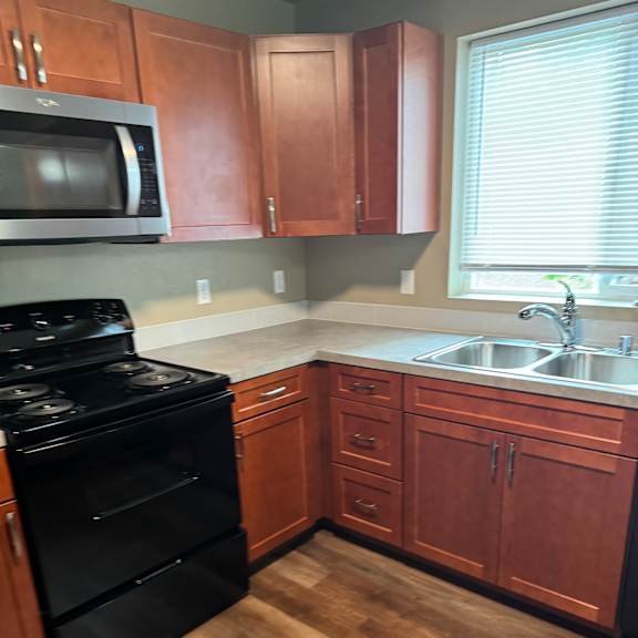 A kitchen with wooden cabinets and black appliances.