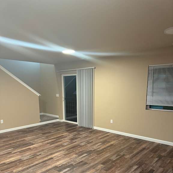 A staircase with a wooden floor and a wall with a window.