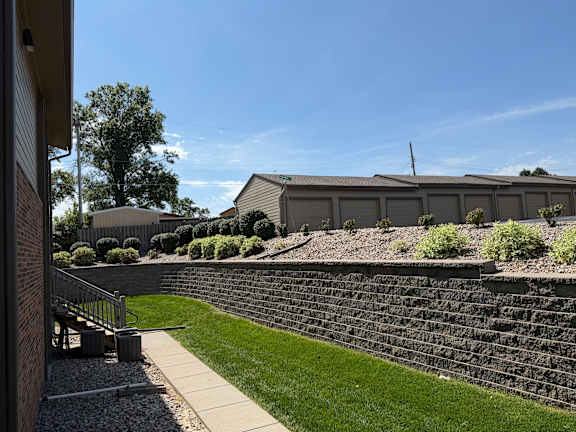 Brick wall and walkway surrounded by green grass at Fox Run Apartments in Omaha, Nebraska