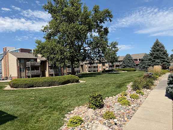 Fox Run Apartments in Omaha, Nebraska near a grassy area with a stone walking path and mature tree