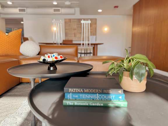 A living room with a round table, a couch, and a potted plant.