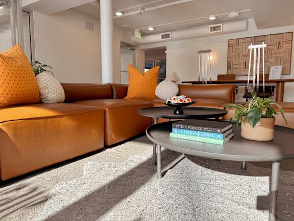 A living room with a brown couch, a grey coffee table, and a potted plant.