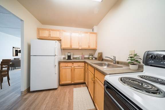 A kitchen with a white refrigerator, wooden cabinets, and a white stove at Highpoint Towers Apartments, Erie, PA