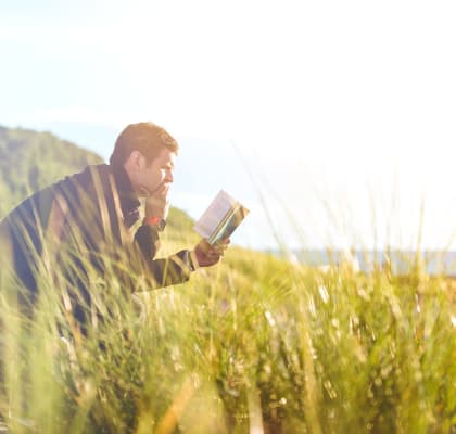a man sitting in the grass reading a book