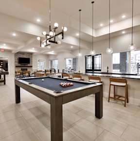 A billiard table is in the middle of a room with a fireplace and a bar area.