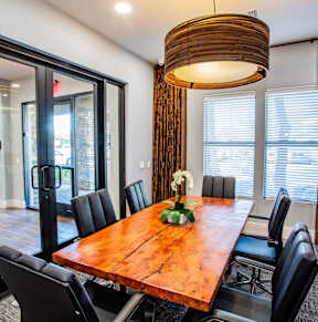 A wooden dining table with black chairs and a hanging light fixture.