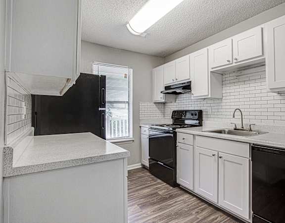 a kitchen with white cabinets and black appliances