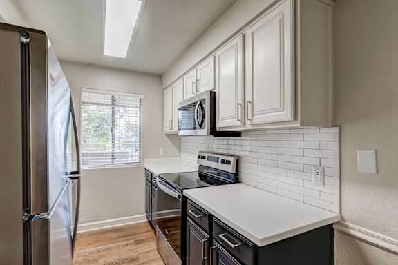 A kitchen with a refrigerator, microwave, and oven.