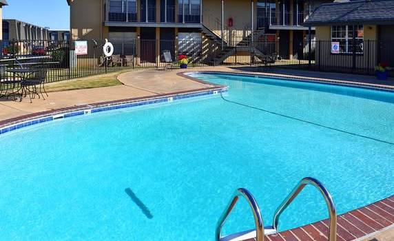 A swimming pool in front of a building with a black fence around it.