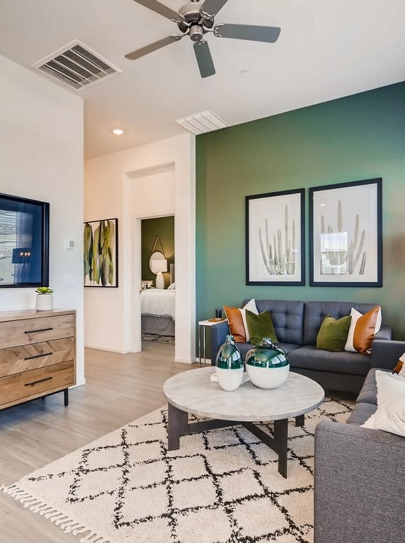 A living room with a grey couch, a coffee table, and a ceiling fan.