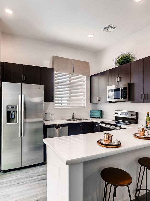 A modern kitchen with a stainless steel refrigerator and dark brown cabinets at Avilla Lehi Crossing, Mesa, 85213