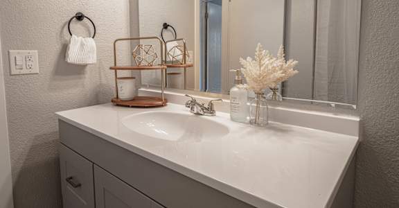 A white bathroom sink with a white towel hanging on the towel ring.