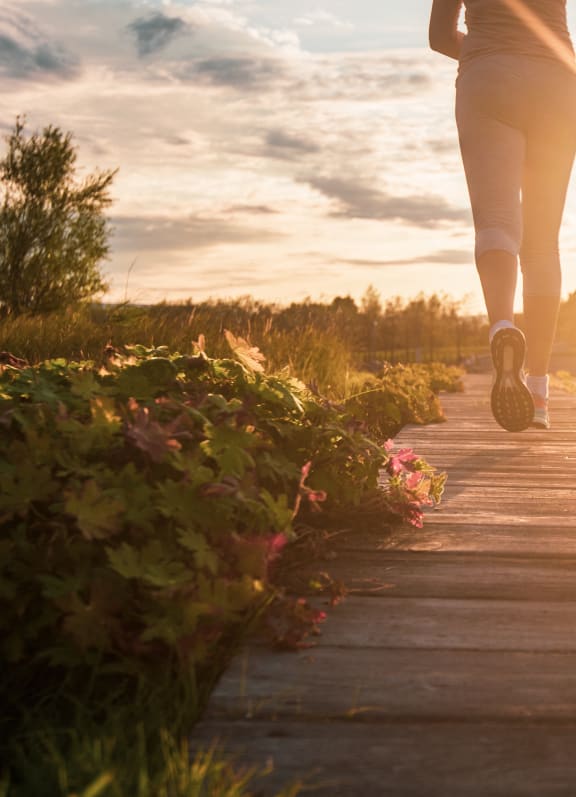 a woman walking on a wooden pathway at sunset