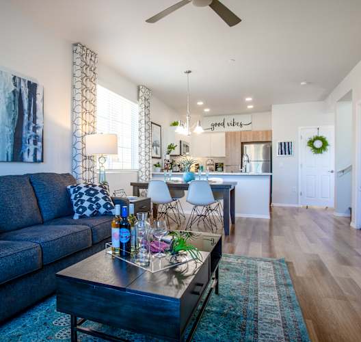 a living room with a blue couch and a coffee table in front of a kitchen with a