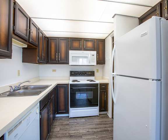 A kitchen with a white refrigerator and brown cabinets.