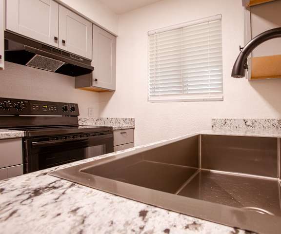 A kitchen with a stainless steel sink and marble countertop.