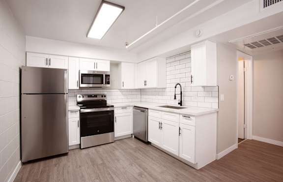 A kitchen with white cabinets and a stainless steel refrigerator.