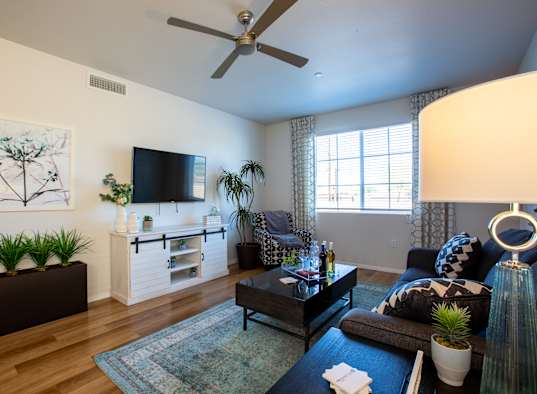 a living room with a ceiling fan and a tv on the wall
