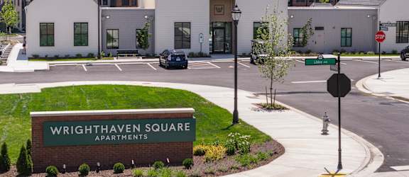 A sign for Wrighthaven Square Apartments is in front of a building.