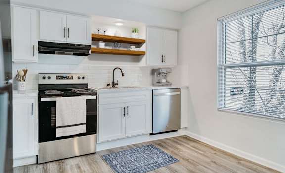 A modern kitchen with a stainless steel oven and white cabinets.