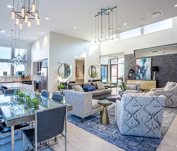 A modern living room with a glass dining table and a grey sofa.
