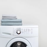 a white washing machine with towels on top of it