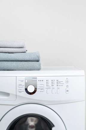a white washing machine with towels on top of it