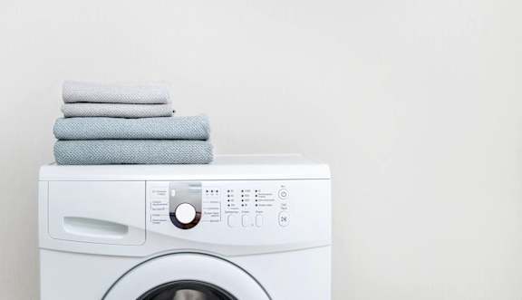 a white washing machine with towels on top of it