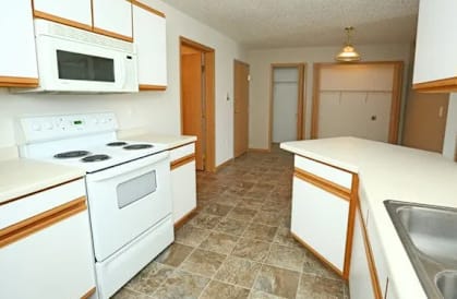 A kitchen with white appliances and brown cabinets.