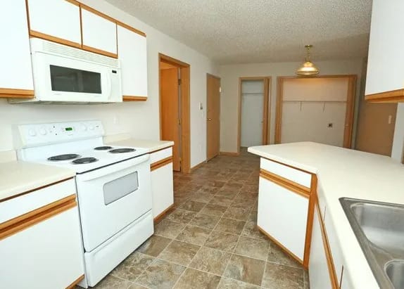 A kitchen with white appliances and brown cabinets.