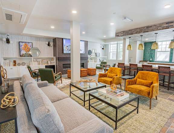 A living room with a grey couch and yellow chairs.