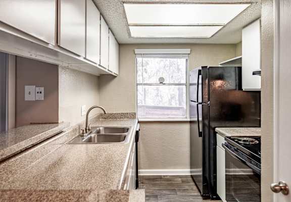 A kitchen with a sink, stove, and refrigerator.