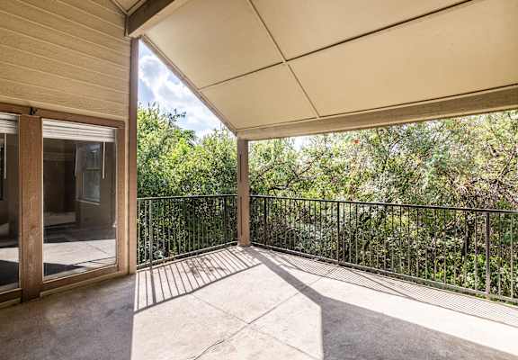 A balcony with a metal railing and a view of trees.