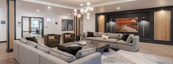 A modern living room with a grey sofa set and a large abstract painting on the wall.