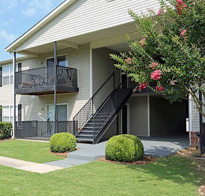 A building with a balcony and stairs leading to the entrance.