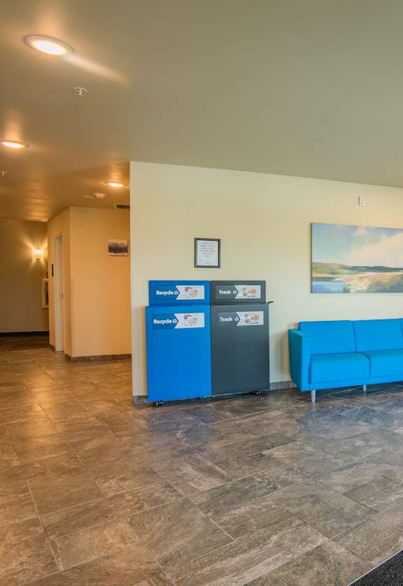 A waiting room with blue chairs and a grey floor.