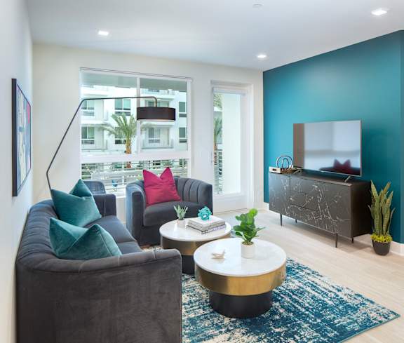 A living room with a grey sofa, a white coffee table, and a blue rug.