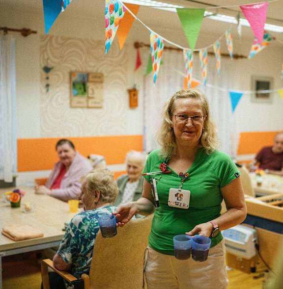A woman in a green shirt is standing in front of a group of people.