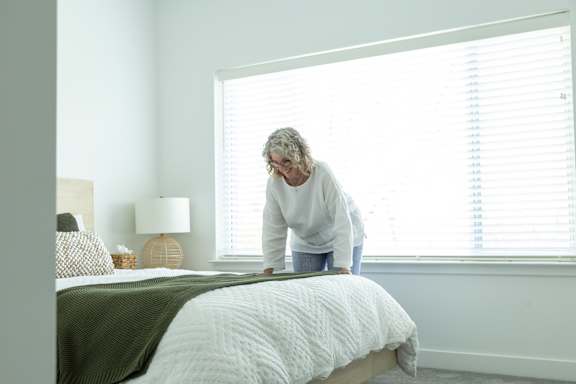 A person is bending over a bed in a room.