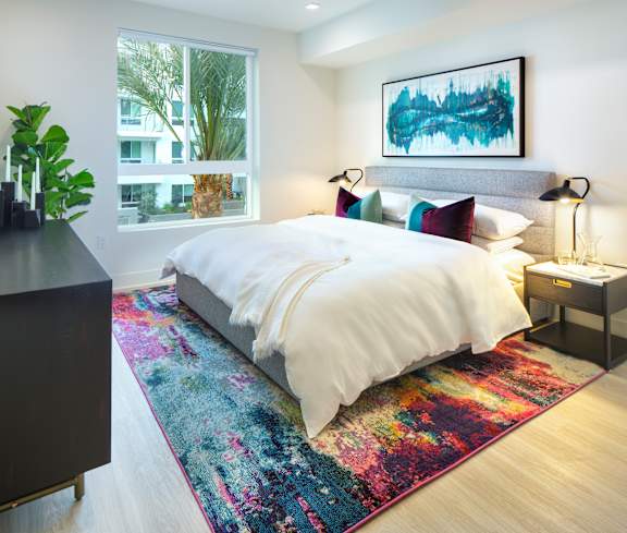 A bedroom with a large bed and a colorful rug.