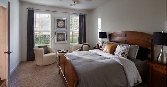 a bedroom with a bed and a chair and a ceiling fan