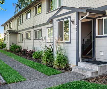 a home with a front door open and a sidewalk in front of it