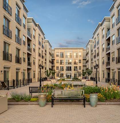 A courtyard with a bench and flower pots in front of apartment buildings.