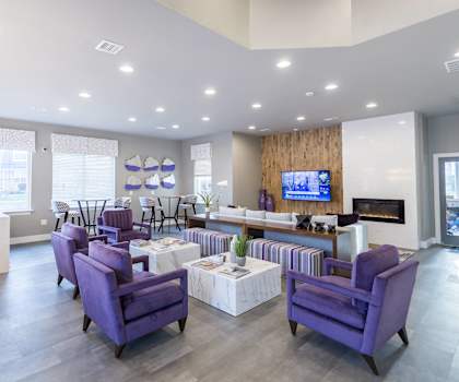 a living room with purple chairs and tables and a television
